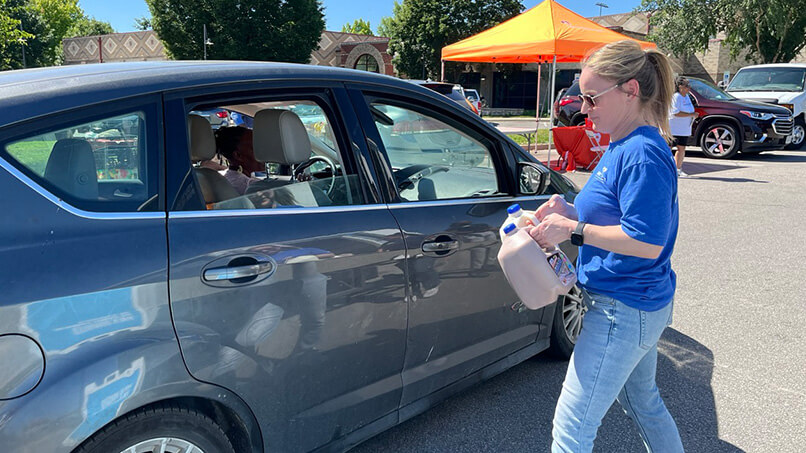 IMG_1075-Large.jpg A volunteer with DFA Cares Foundation prepares two gallon jugs of milk for a car.